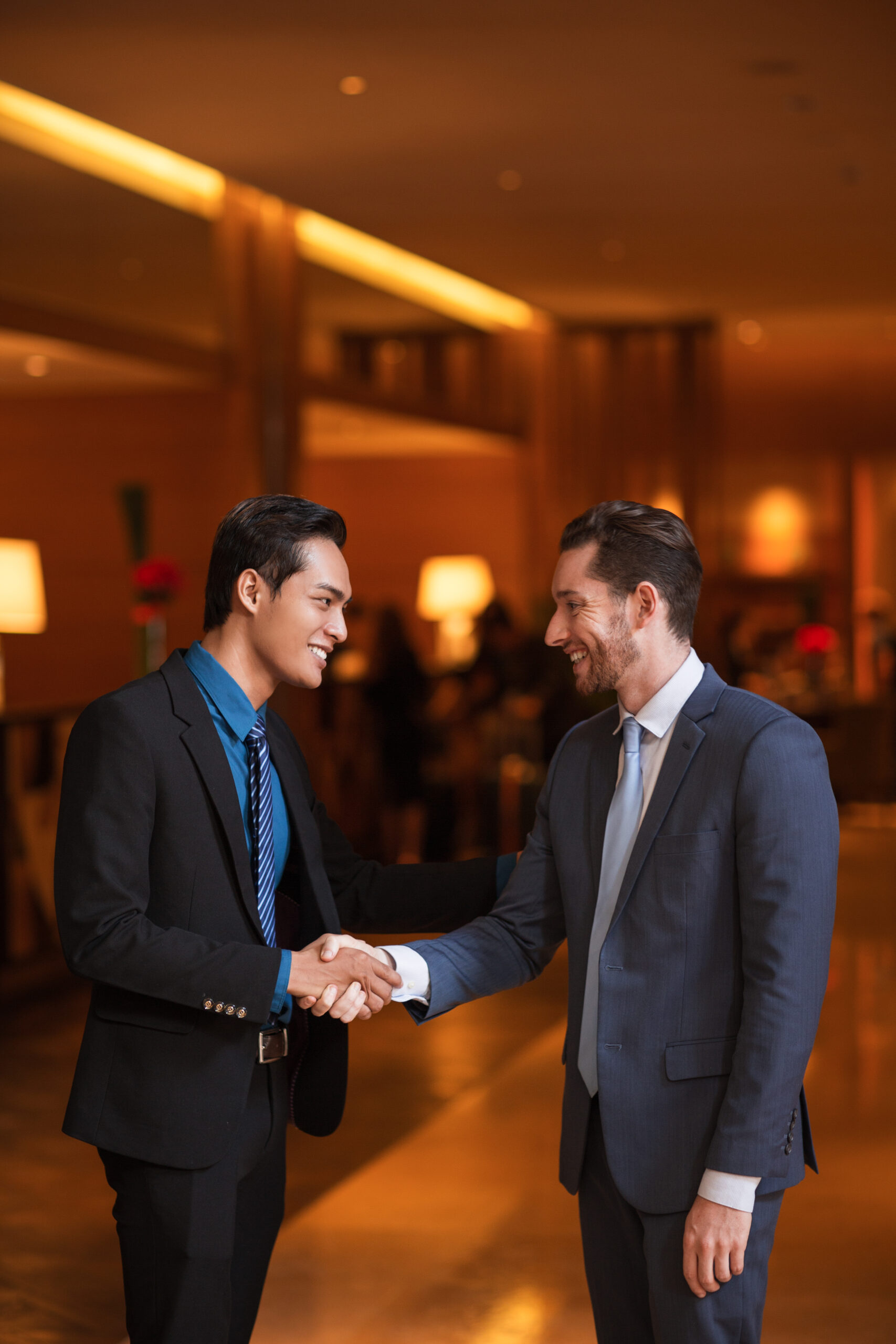 two smiling partners shaking hands in lobby